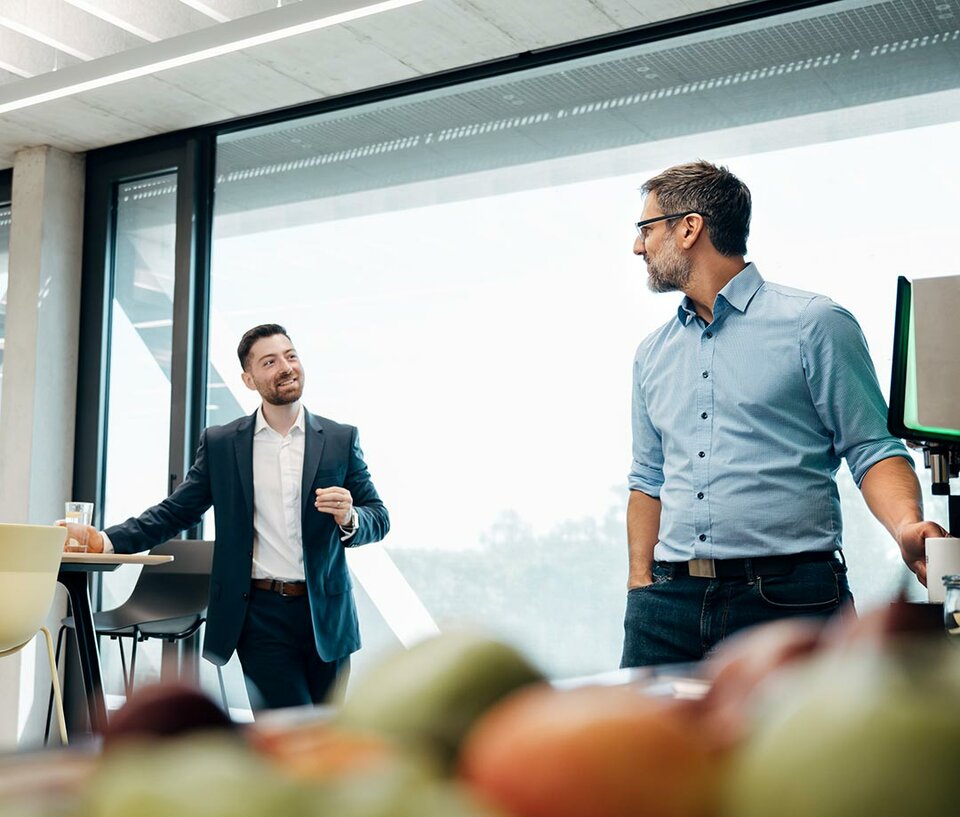 igz benefits kostenloses obst und getraenke 2 Mitarbeiter unterhalten sich neben Tablett mit Obst