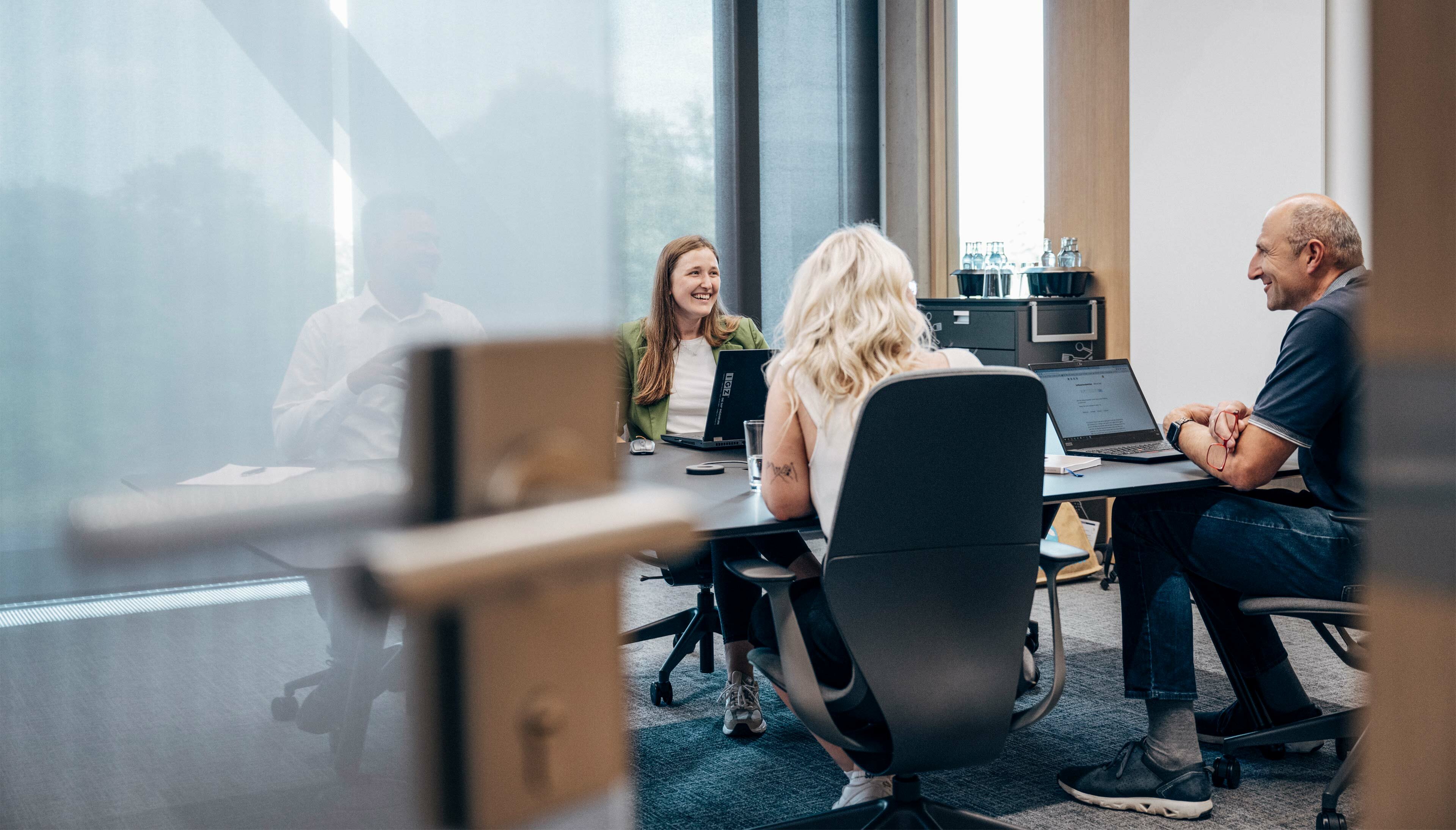 drei mitarbeitende sprechen in einem workshopraum miteinander