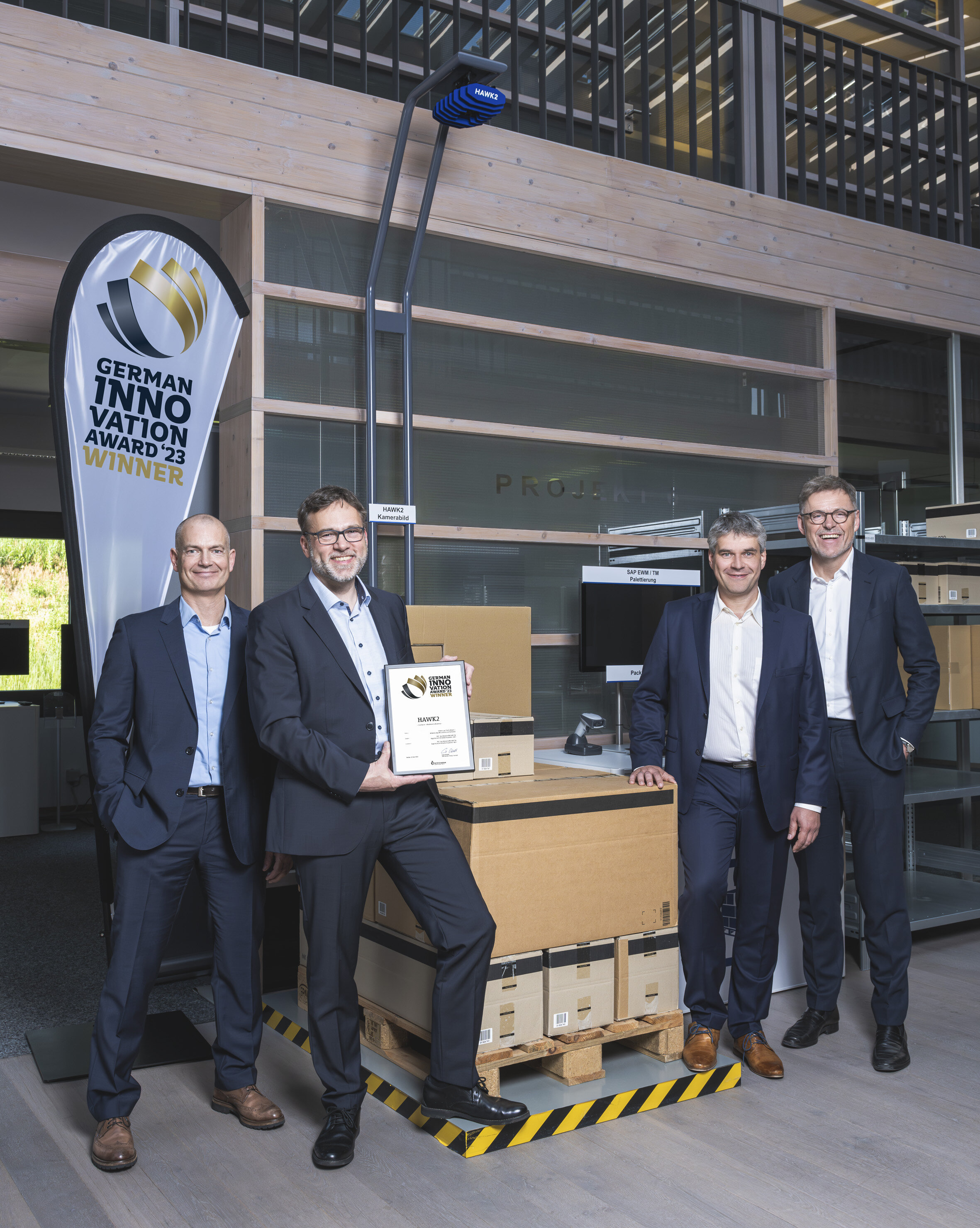 Vier Männer in Anzügen grinsen in die Kamera und halten den Award GIA 2024 | IGZ