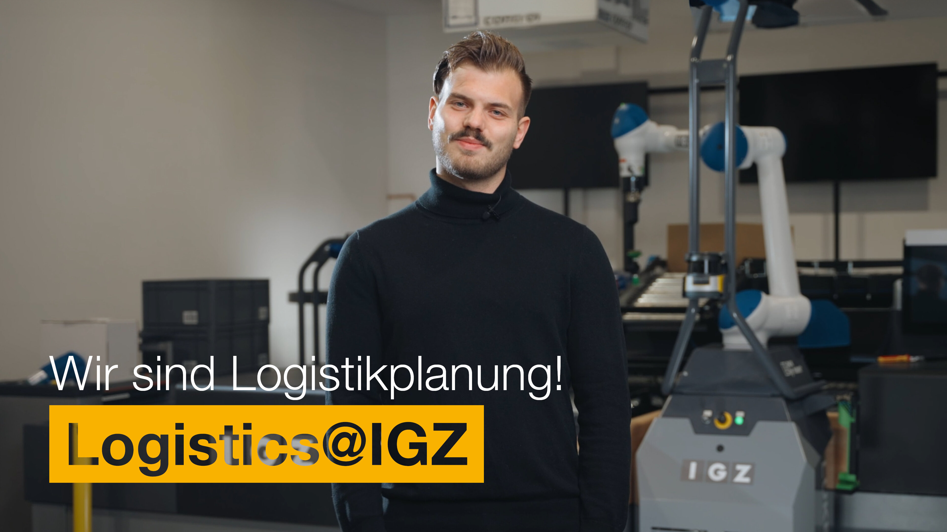 Mann mit Rollkragenpullover steht vor Maschine | Wir sind Logistikplanung | Logistics@IGZ: | IGZ